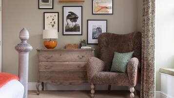 A cozy room with a wooden dresser, a plush armchair, and a decorative lamp.