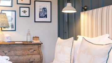 A bedroom with a wooden dresser, a bedside lamp, and framed artwork on the wall.