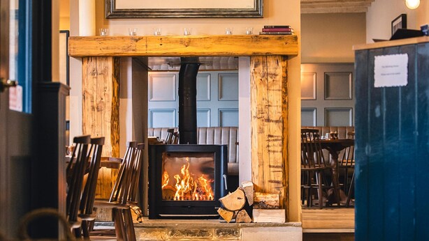 A cozy room with a fireplace, wooden furniture, and a stone fireplace surround. - The Whittling House (Alnwick)