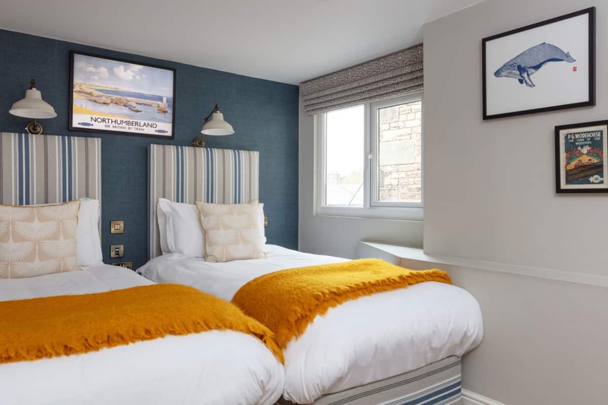 A hotel room with two beds, a window with a view, and framed pictures on the wall.