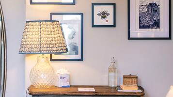 A wooden table with a lamp, framed artwork, and a tissue box.
