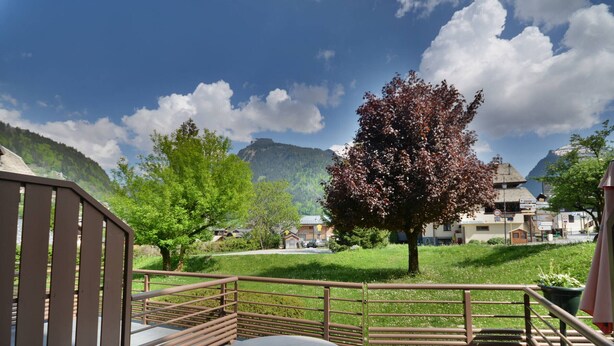 A terrace with a table and chairs, a metal railing, and a view of a mountain and buildings in the background. - Duplex Studio 5 pers. in Central Morzine, near Slopes (Morzine)