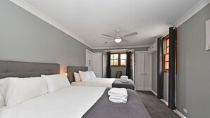 Une chambre d’hôtel avec deux lits, un ventilateur de plafond, une fenêtre avec des rideaux et une porte.