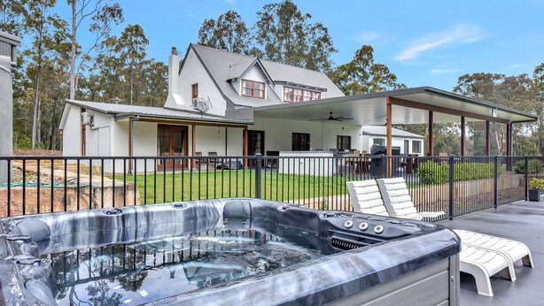 Une propriété résidentielle dotée d’un jacuzzi, d’un patio couvert et d’une grande maison avec une pelouse.
