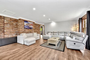 A modern living room with a brick wall, two sofas, a coffee table, and a large window with curtains.