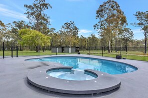 A swimming pool with a circular hot tub in the center, surrounded by a fence and trees. - Kitchener Country Estate with Pool Hot Tub (Kitchener)