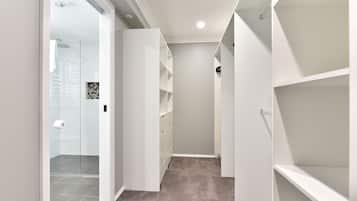 A narrow hallway with white shelving units on both sides, a glass door entrance, and a carpeted floor.