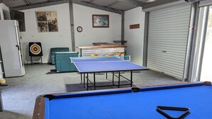 Une table de billard recouverte d’un drap bleu, avec une queue de billard placée au premier plan.