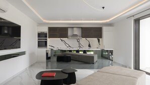 A modern kitchen with a marble backsplash, integrated appliances, and a central island. - Ivory Villa, Heated Pool, Hot Tub, Sauna & Gym (Perama)