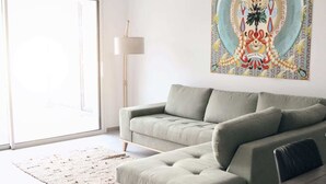 Una sala de estar moderna con un sofá seccional gris, una mesa de comedor de madera y un cuadro abstracto y colorido en la pared.