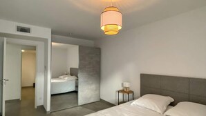 Una habitación de hotel moderna con una cama grande, una mesita de noche con una lámpara y un aplique de techo.