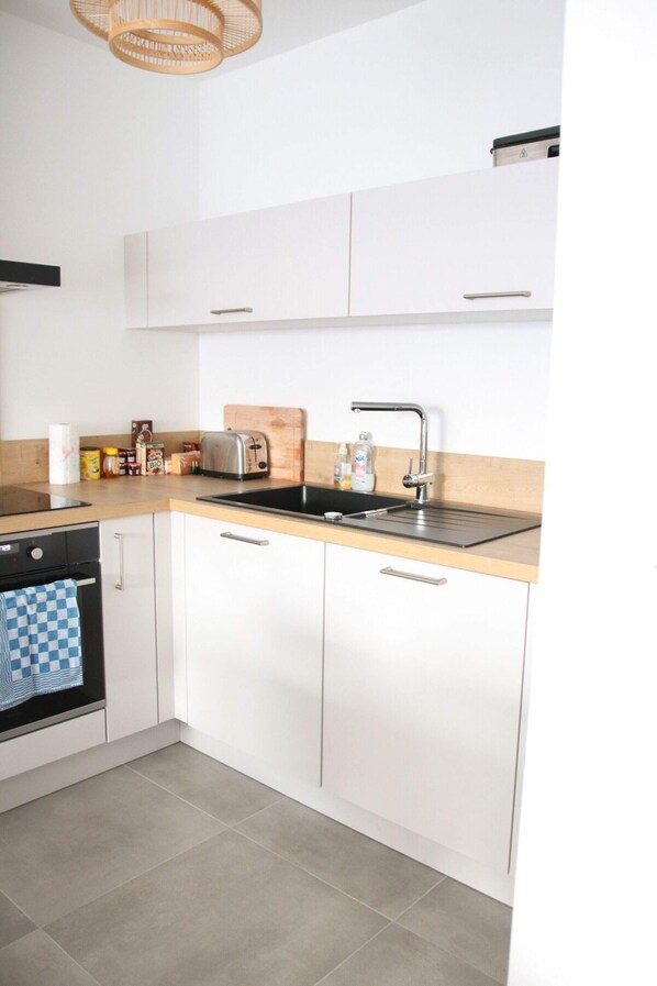 Une cuisine moderne avec des meubles blancs, un évier en acier inoxydable et un plan de travail en bois.