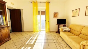 A living room with a yellow sofa, a television, and a cabinet. - Lovely 6-bed Apartment on the Amalfi Coast (Amalfi)
