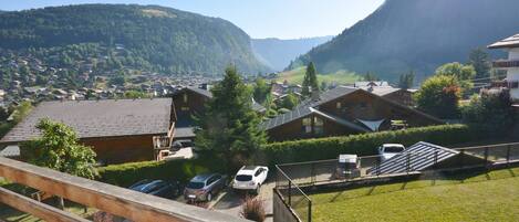 A residential area with houses, a parking area, and a mountain backdrop.