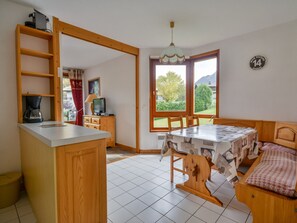 Uma cozinha compacta com cafeteira, televisão e área de refeições com mesa e cadeiras.