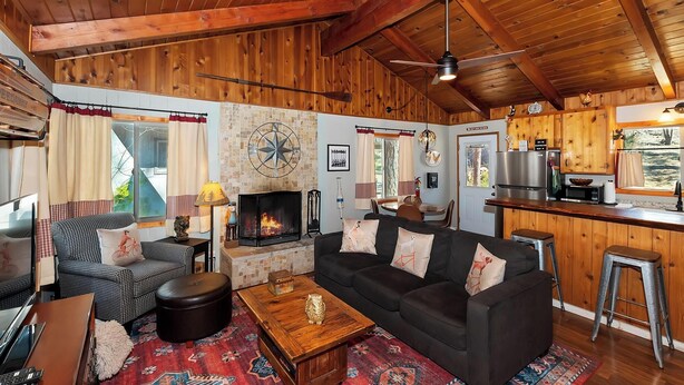 Un acogedor interior de cabaña con chimenea, techo de madera y una zona de cocina.
