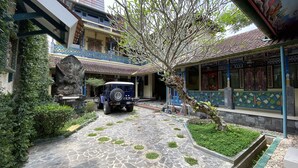 A courtyard with a stone pathway, a parked jeep, and a statue. - Omah Eling Medang Kamulan Borobudur (Borobudur)