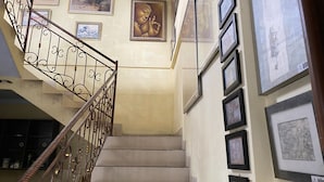 A staircase with a wrought iron railing, beige walls, and framed artwork. - Omah Eling Medang Kamulan Borobudur (Borobudur)