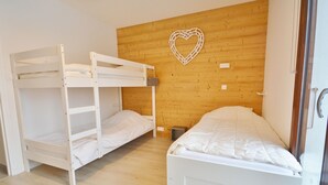 Een kamer met stapelbedden en een eenpersoonsbed, houten wanden en een decoratie in de vorm van een hart.