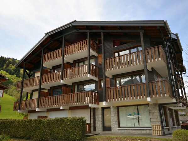 A multi-story building with balconies, large windows, and a stone facade.