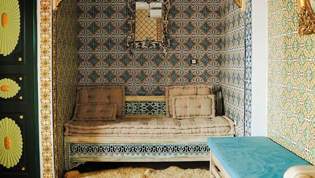 A room with a patterned tile wall, a sofa, a bench, and a small table. - Bit HSAN :Original guestroom (Mahdia)