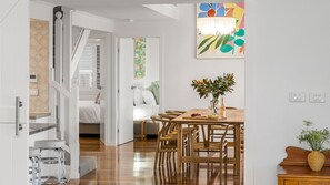 Una cucina moderna con un tavolo da pranzo in legno, sedie e un vaso con fiori.