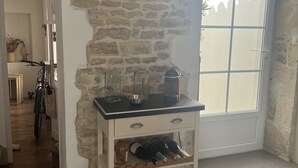 Una stanza con parete in pietra, un orologio grande, una finestra vista e una dispensa per vino.