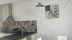 Una cucina compatta con isola centrale, un tavolo da pranzo con sedie e un'opera d'arte a tema bicicletta appesa al muro.