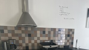 Una cucina moderna con forno integrato, macchina da caffè e cappa aspirante.