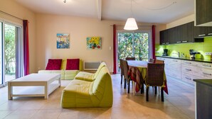 Una sala de estar moderna con un sofá, una mesa de comedor con sillas y una cocina con armarios y encimera.