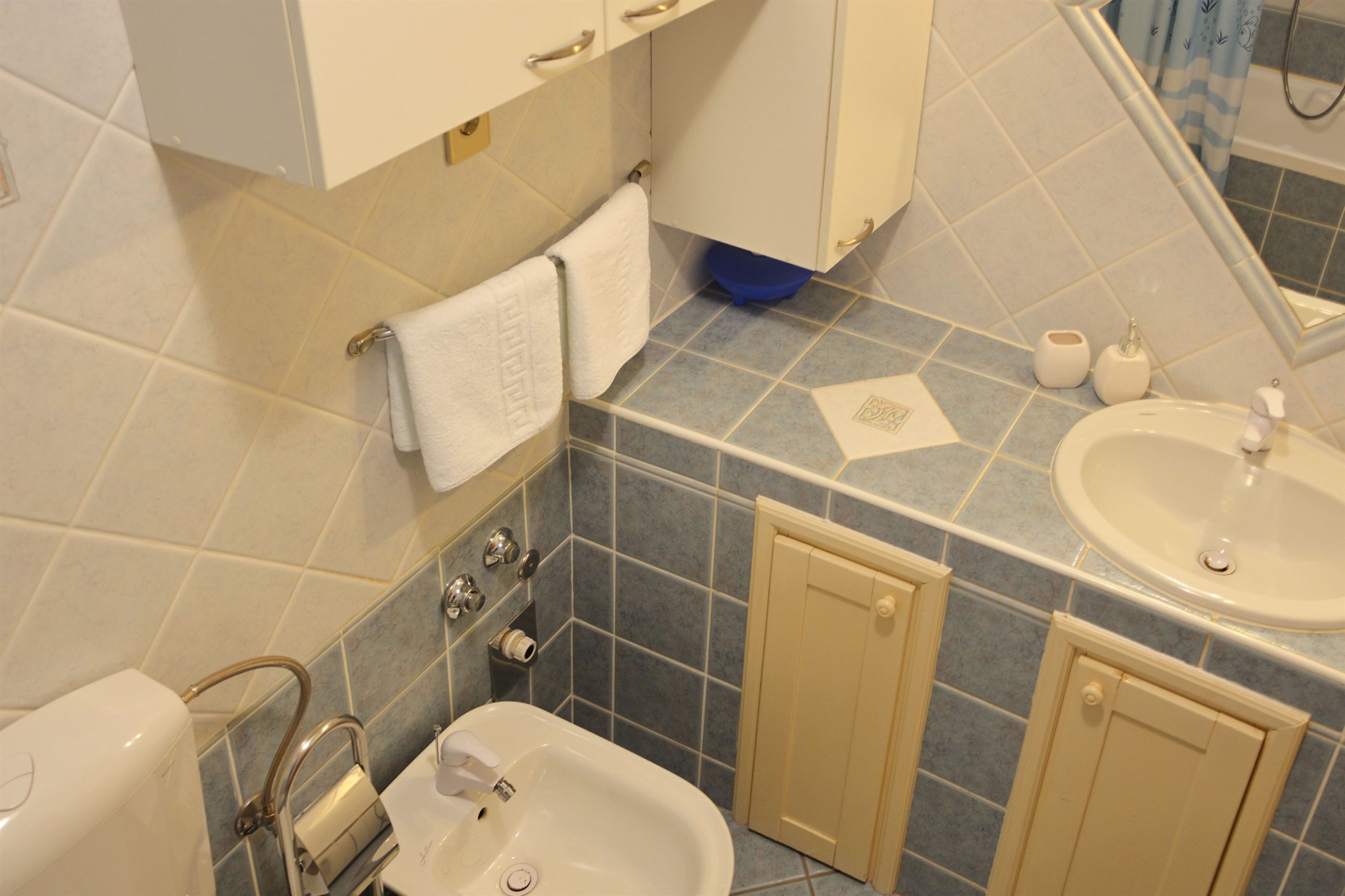 Un baño con lavabo, espejo, toallero y retrete.