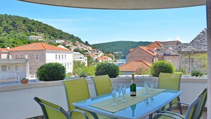 Eine Terrasse mit Tisch für vier Personen mit Blick auf ein Hügel-Dorf und traditionelle Häuser.