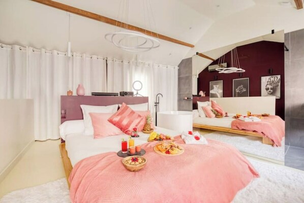 A modern bedroom with a large bed, a vanity, and a mirror.
