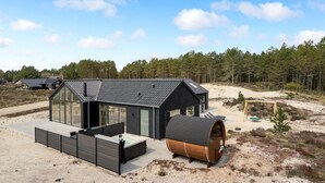 Et moderne hus med stor glasfacade, jacuzzi og en træstandtønde.