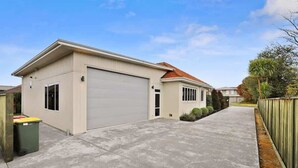 Ein eingeschossiges Haus mit Garage, Auffahrt und umzäunter Garten.