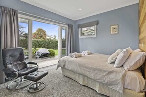 A bedroom with a bed, a chair, a window, and a view of the outdoors.