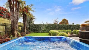 Ein Garten mit Whirlpool, Holzzaun und unterschiedlichen Pflanzen.