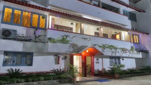 A multi-story building with a central entrance, balconies, and outdoor plants. - Harmony House - A Boutique Hotel (Guwahati)