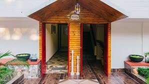 A hotel entrance with a wooden facade, a red door, and a sign that reads "Harmony." - Harmony House - A Boutique Hotel (Guwahati)