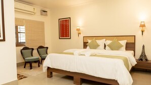 A hotel room with a large bed, two chairs, a nightstand with a lamp, and a decorative Eiffel Tower. - Harmony House - A Boutique Hotel (Guwahati)