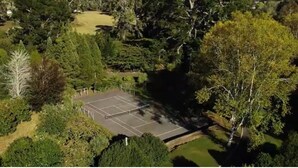 An aerial view of a tennis court surrounded by dense greenery. - Lakeside Paradise (Rotorua)