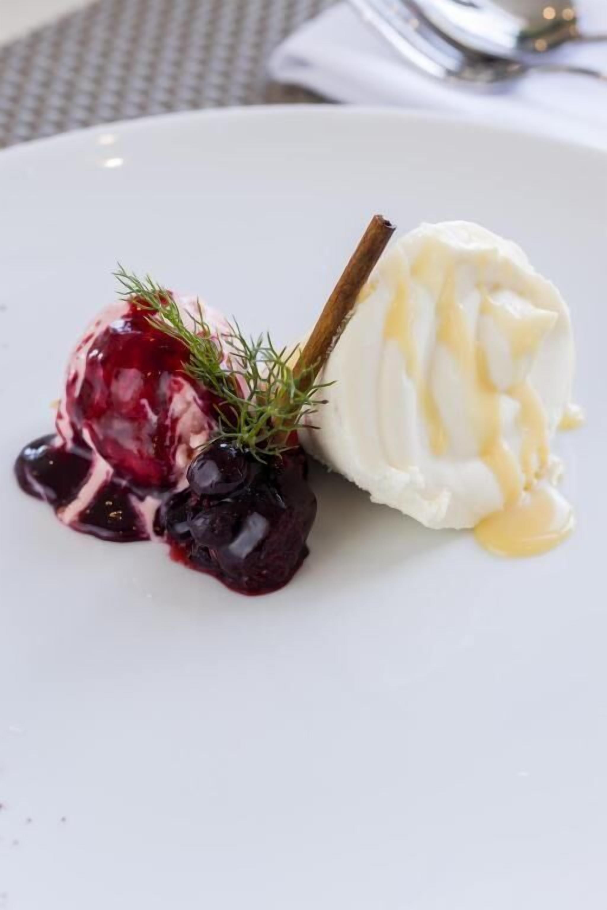 Postre con bayas y una ramita de romero sobre un plato blanco.
