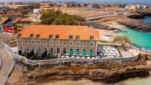 Ein Küstenhotel mit Terrasse mit Meerblick, einem Schwimmbad und einem Strandbereich.