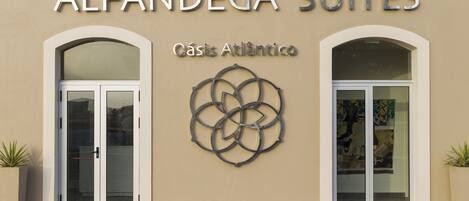 The exterior of Alfãndega Suites with a modern design, featuring two arched doorways and a decorative metal piece above the entrance.