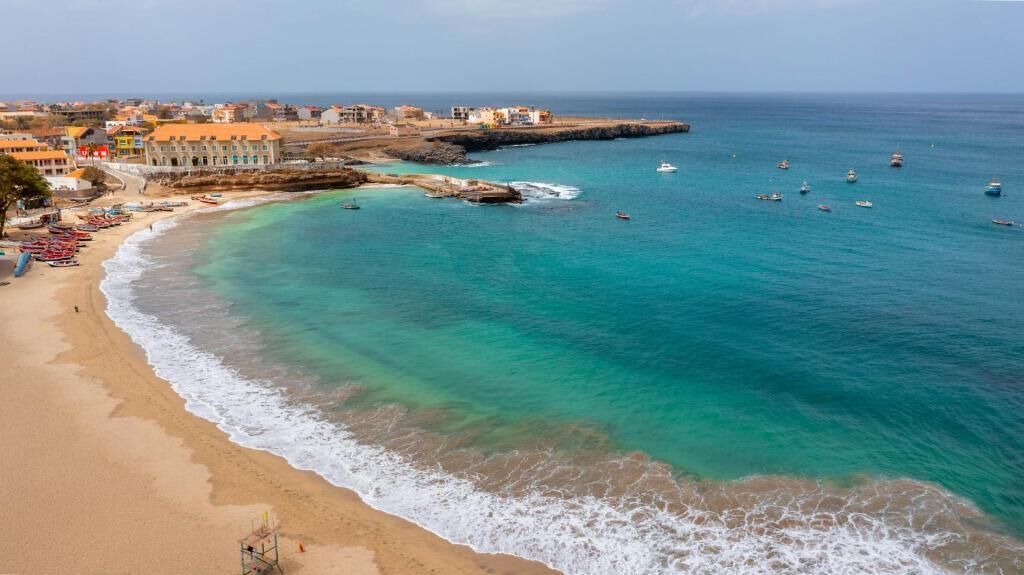 A coastal town with a beach, boats, and buildings along the shore.