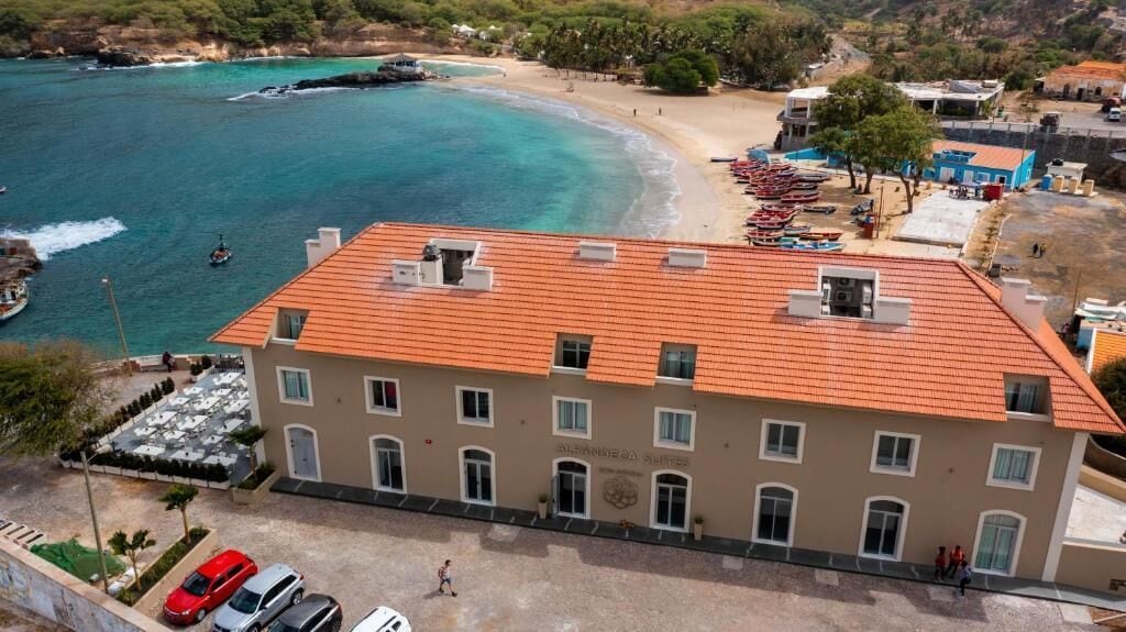 Un edificio con techo de tejas rojas, múltiples ventanas y un letrero que indica que es un hotel.