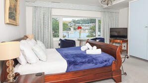 A hotel room with a bed, a TV, a desk, and a view of a marina.