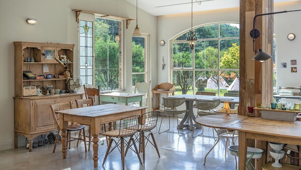 Une cuisine spacieuse dotée de grandes fenêtres, de meubles en bois et d’un coin repas avec une table et des chaises.