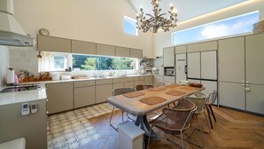 Une cuisine moderne dotée d’un grand îlot central, d’appareils électroménagers intégrés et d’un coin repas avec des chaises en osier.