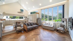 Un vaste espace de vie agrémenté d’une grande fenêtre, d’un parquet en bois disposé en point de Hongrie et d’une cuisine moderne dotée de nombreux plans de travail.